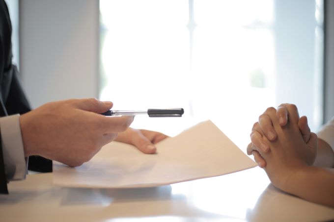 Businessman handing out a contract and pen to a person to sign
