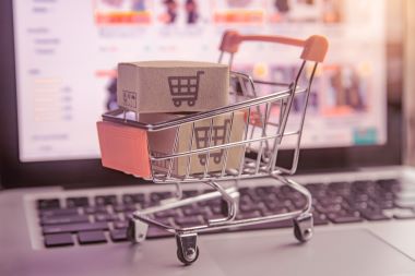 Parcel or Paper cartons with a shopping cart logo in a trolley on a laptop keyboard. 